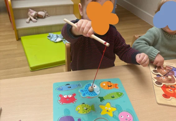 Petit garçon joue au puzzle magnetique dans une crèche